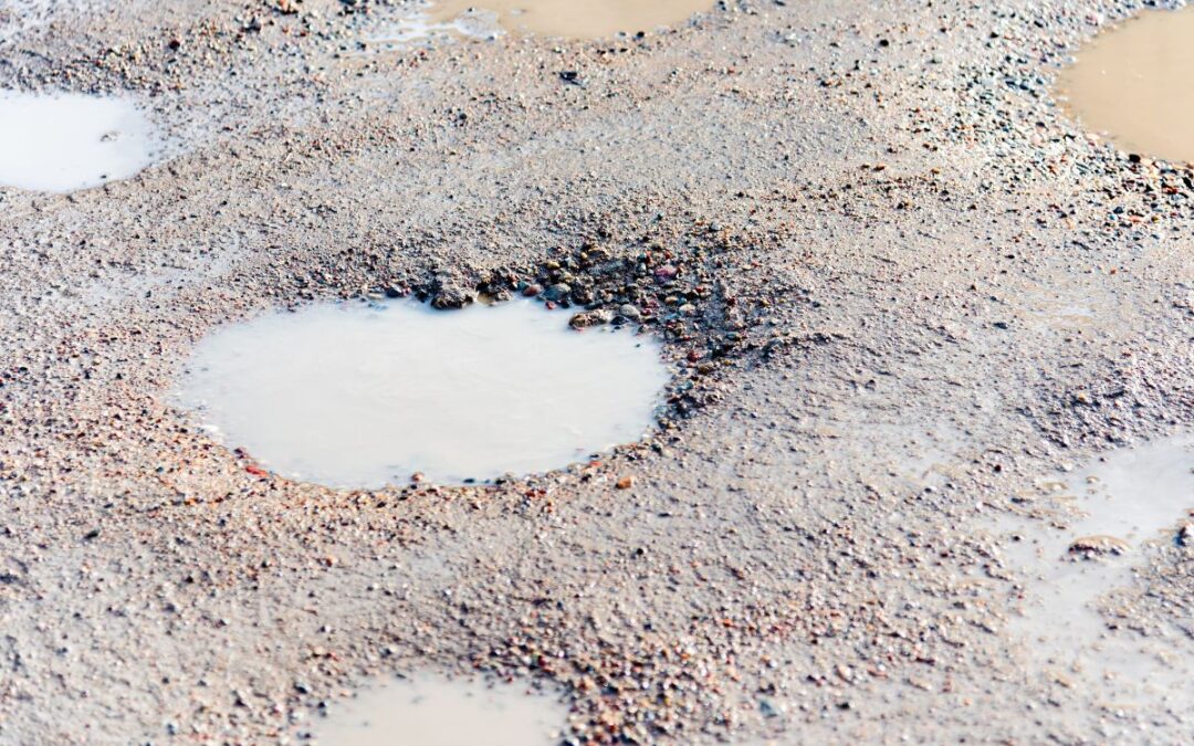 pothole on a gravel driveway filled with water